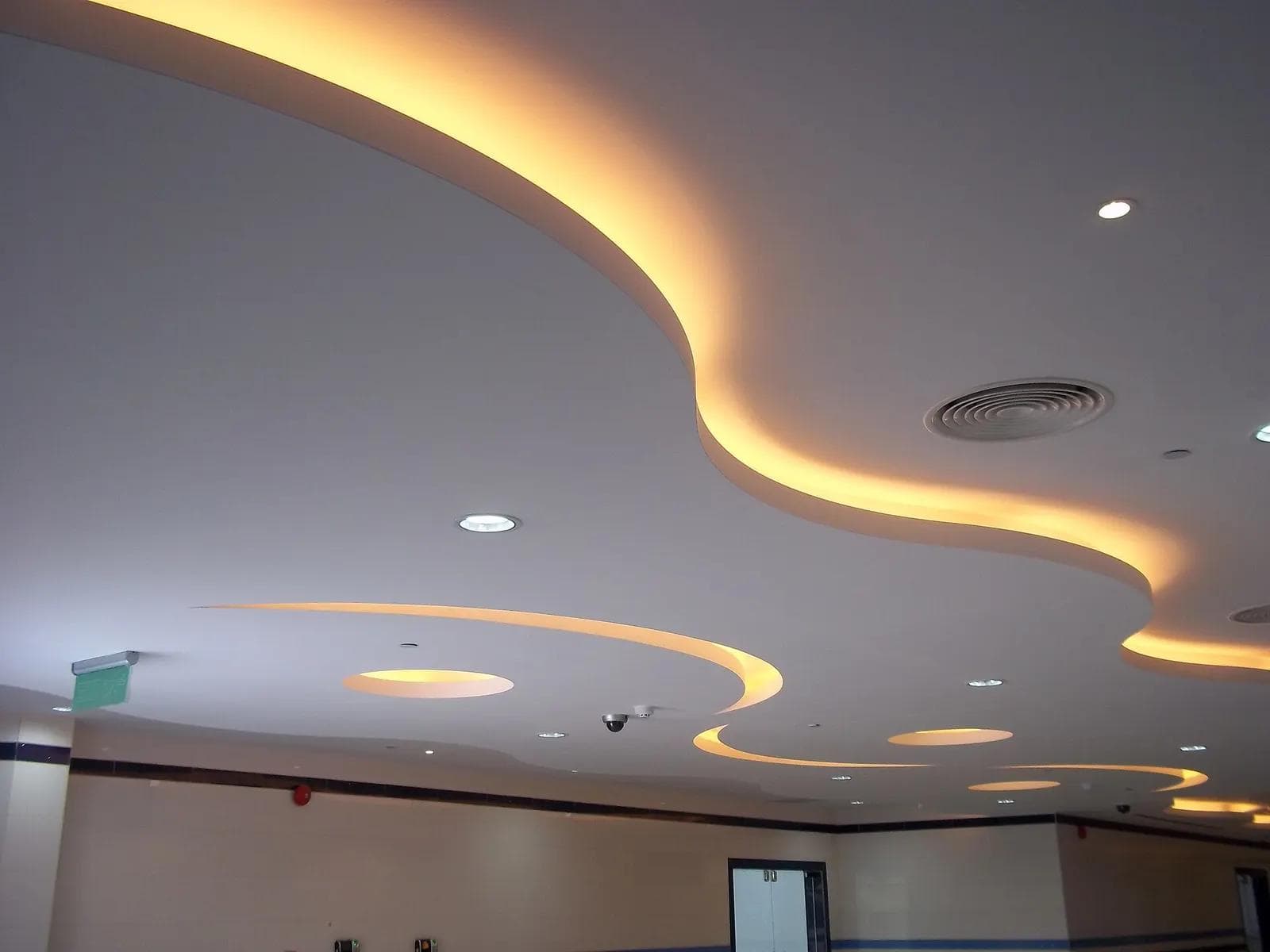 Curved false ceiling with warm cove lighting and recessed lights