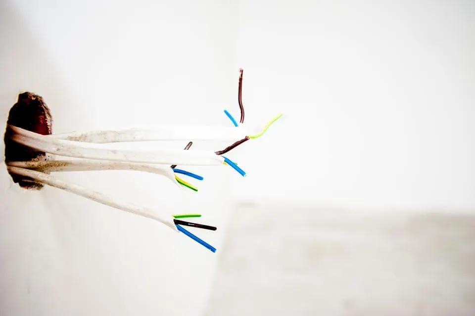 Electrical wires coming out of a wall opening before fitting