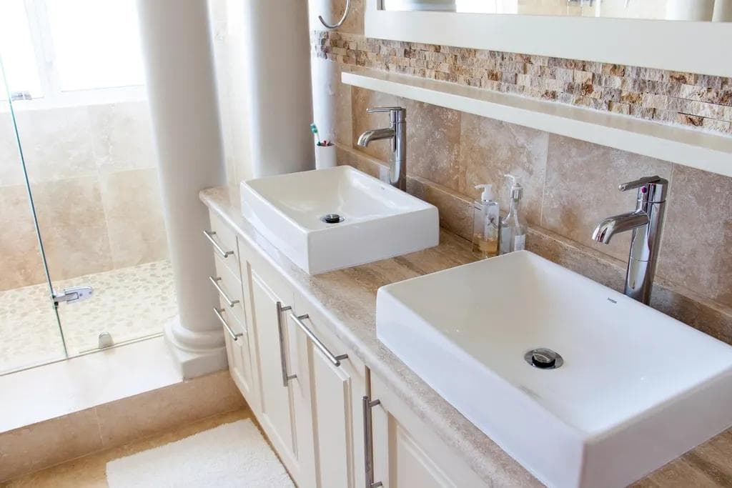 Two white countertop wash basins with chrome taps